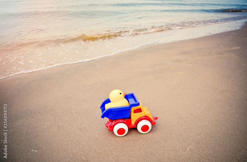 Yellow duck toy and colorful car on sand in the beach Yellow duck toy and colorful car on sand in the beach