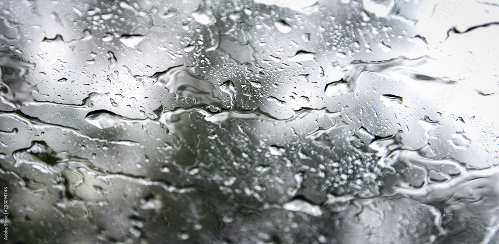 Rain drops on glass / Rainy day window glass with water drops and nature blur background