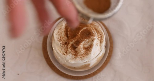 Sprinkling with cinnamon powder on espresso con panna with whipping cream