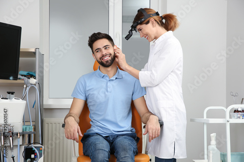 Professional otolaryngologist examining man in clinic. Hearing disorder photo