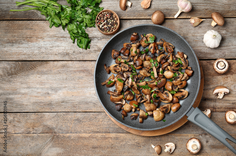 Frying pan of mushrooms on wooden background, flat lay with space for text Frying pan of mushrooms on wooden background, flat lay with space for text