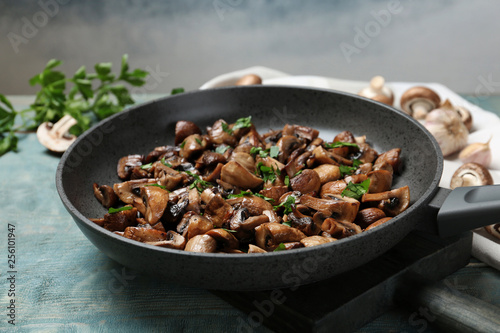 Frying pan with mushrooms on wooden table, closeup
