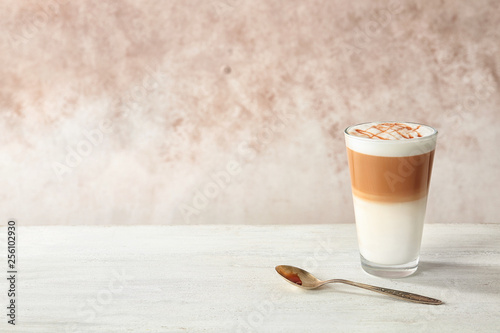 Tableau sur toile Glass of caramel macchiato on table against color background