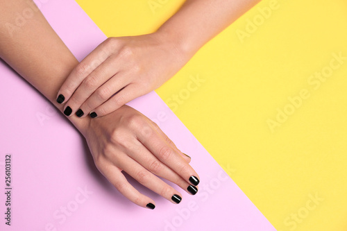 Woman with black manicure on color background  top view and space for text. Nail polish trends