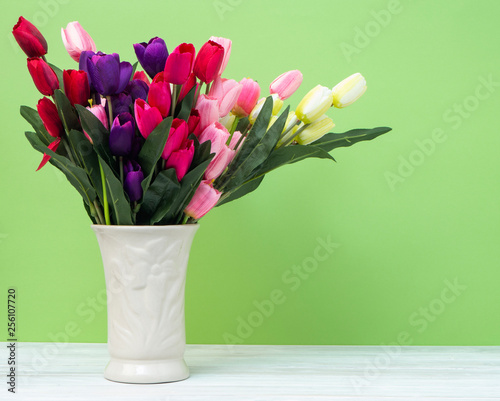 Wallpaper Mural Colorful tulips in vase on white table wall green background Torontodigital.ca