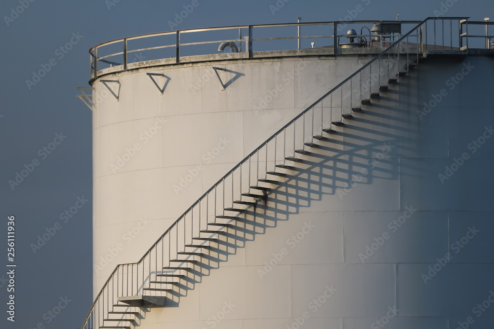 large white Industrial tanks for petrol and oil , shadows of the stairs.