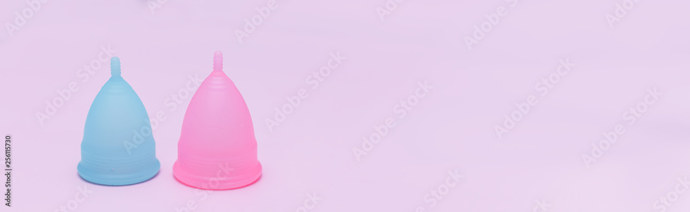 Two pink and blue period menstrual cup on a pink background. Concept of women's health, hygienic means of protection, menstruation, ecology of the planet.