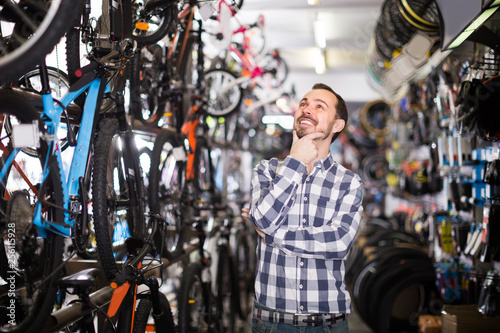 Man 29-35 years old is choosing in sports store convenient bike