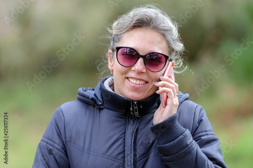 woman in sunglasses talking on a mobile phone in the forest
