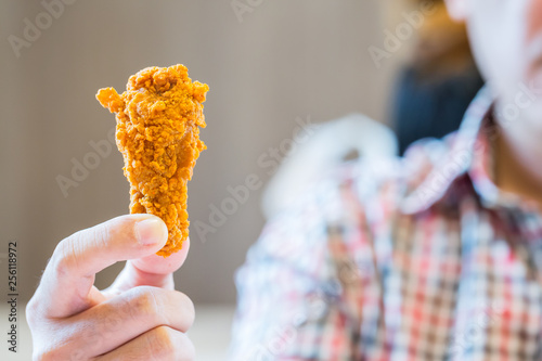 man is holding deep fried chicken drumstick