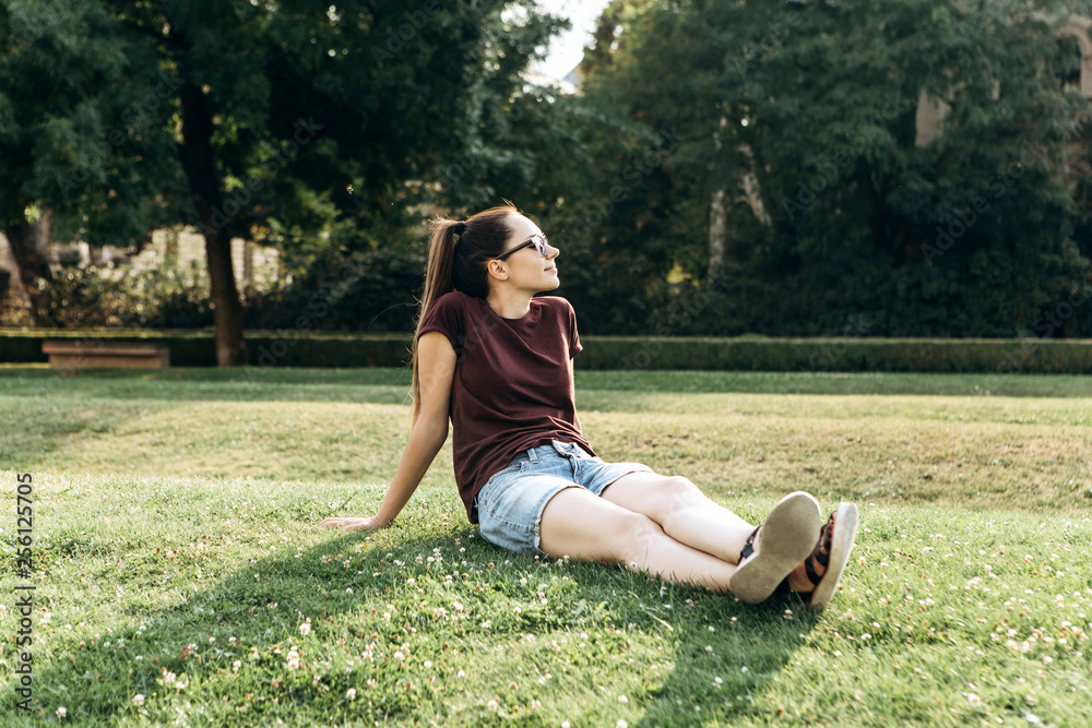 Beautiful young girl resting on the grass in a city park. Beautiful young girl resting on the grass in a city park.