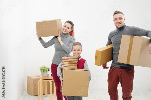 Young family, man woman and child son in new apartments. Carried in the hands of cardboard boxes. Boxes with cargo on a white background.