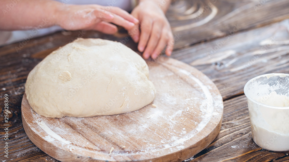 dough in the hands of a child, a wooden table. dough in the hands of a child, a wooden table.