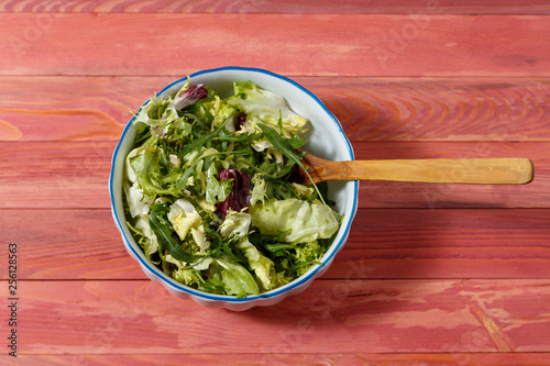 Fresh vegetarian salad from escariol, frieze, radicio, arugula in a white plate on a wooden background. photo