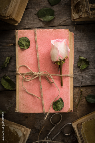 Pink rose on an old book in a vintage style.