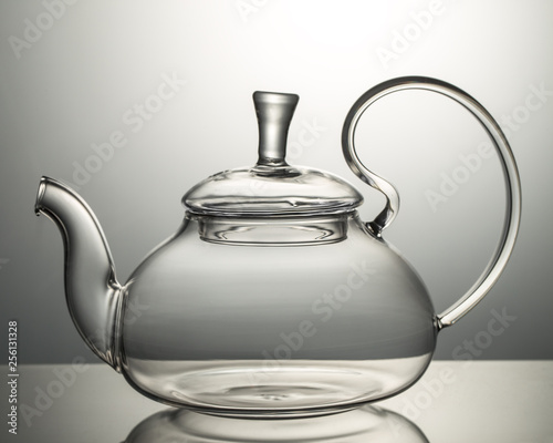 Empty glass teapot on a gray background photo