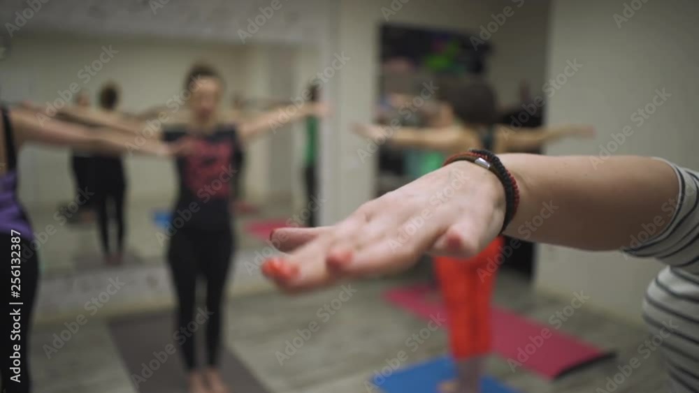 close view group of young women does wrist extension and stretching exercises standing on carrymats at yoga class close view group of young women does wrist extension and stretching exercises standing on carrymats at yoga class