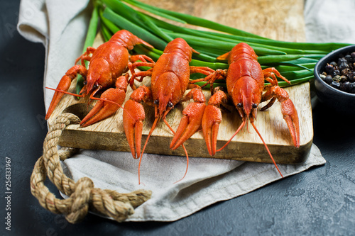 Cooked crayfish on a wooden chopping Board. Black background, side view, close-up. photo