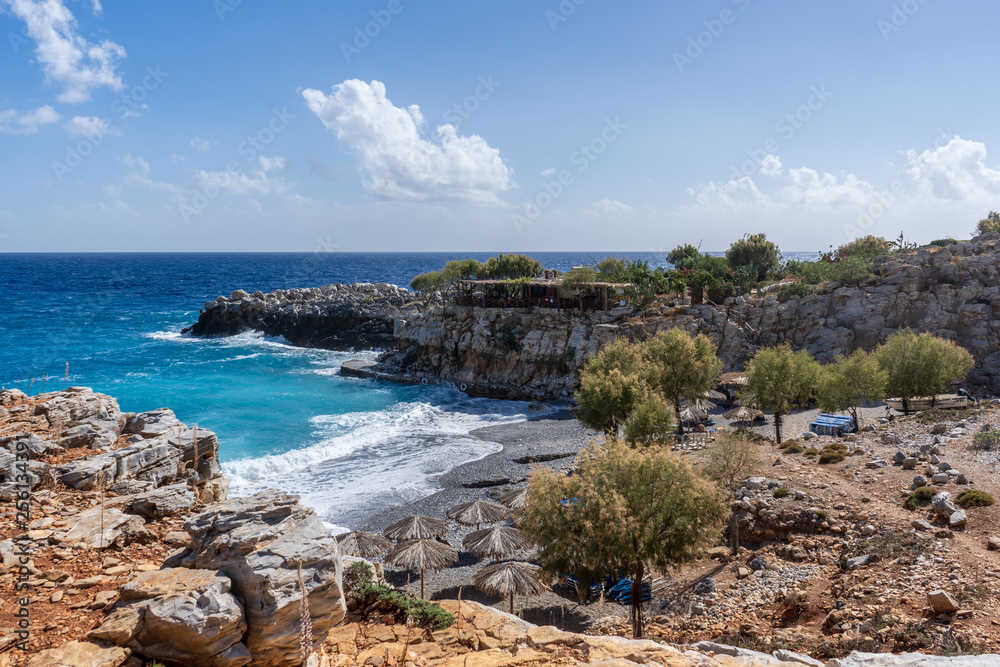 View over bay of Marmara Beach with parasolas on the beach and turquoise waters in front of a tavern near the Aradena gorge on Crete island, Greece