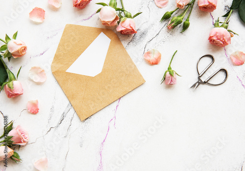 Spring holiday theme, roses and letter on a white marble background