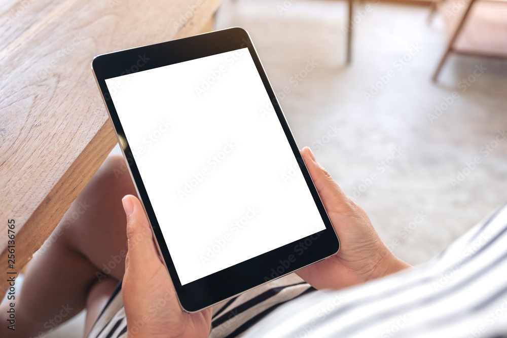 Mockup image of a woman sitting and holding black tablet pc with blank white desktop screen Mockup image of a woman sitting and holding black tablet pc with blank white desktop screen