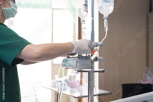 Fotografie Close up nurse hand adjust infusion pump set iv fluid intravenous drop saline drip in hospital room