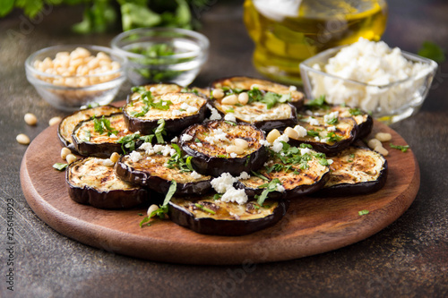 Fried eggplant with feta, pine nuts, fresh herbs (cilantro, parsley) and olive oil. Tasty vegetable snack, summer, spring food, picnic
