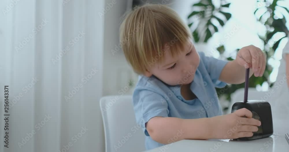 Boy sharpening a pencil sitting at the table Boy sharpening a pencil sitting at the table