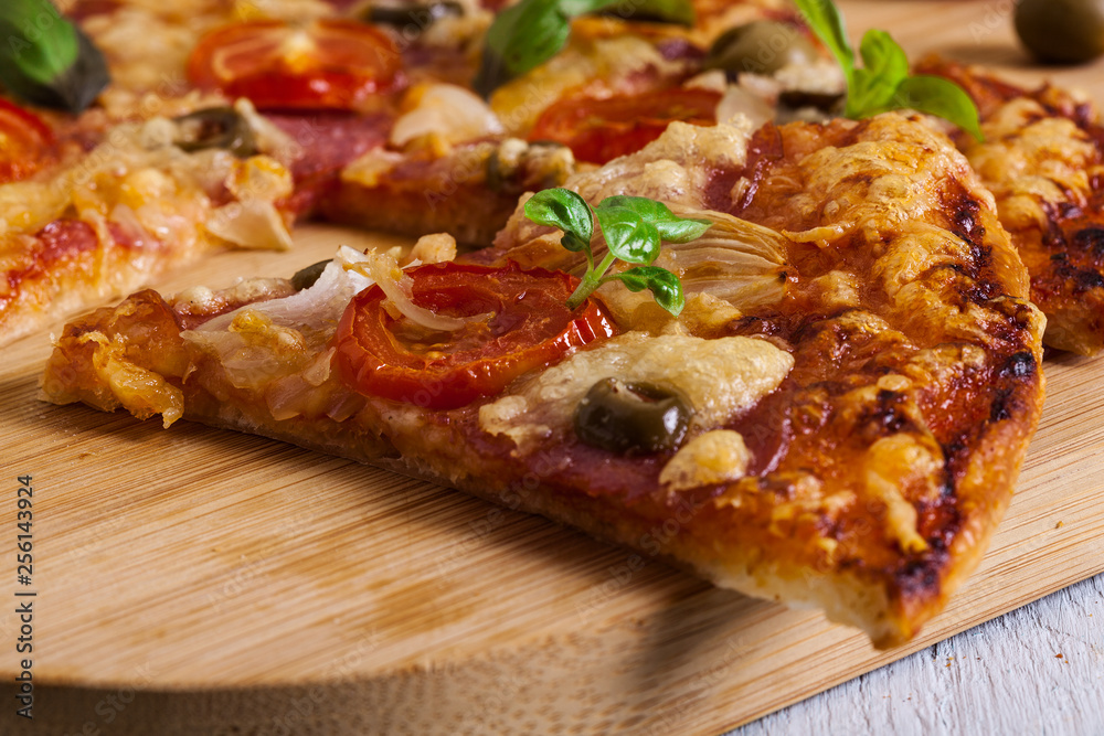 Slices of pizza with bacon, olives and tomatoes Slices of pizza with bacon, olives and tomatoes