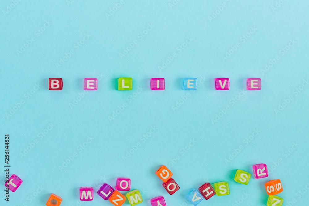 believe inscription made of colorful cube beads with letters. Festive blue background concept with copy space.. believe inscription made of colorful cube beads with letters. Festive blue background concept with copy space..