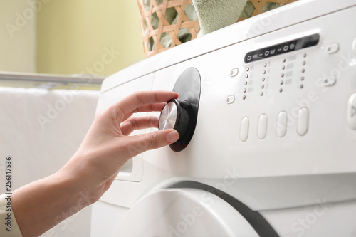 Woman switching on washing machine, closeup