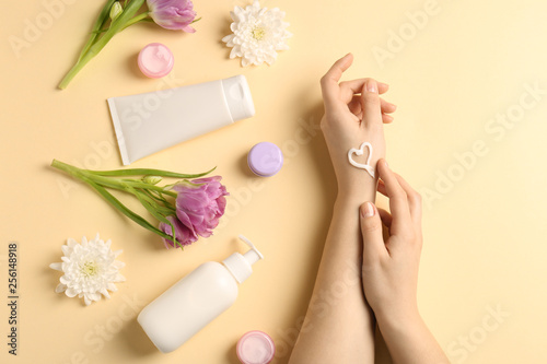 Female hands with natural cream on color background