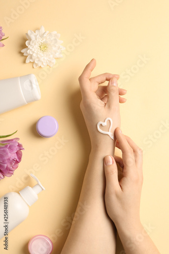 Female hands with natural cream on color background