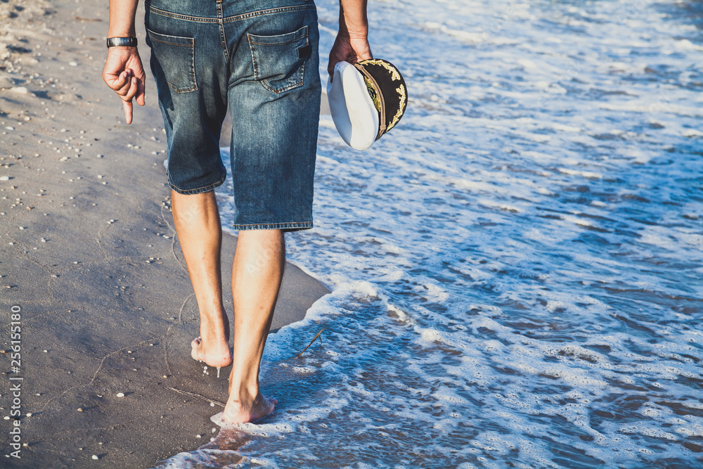 Man walks on the sea beach - obrazy, fototapety, plakaty 
