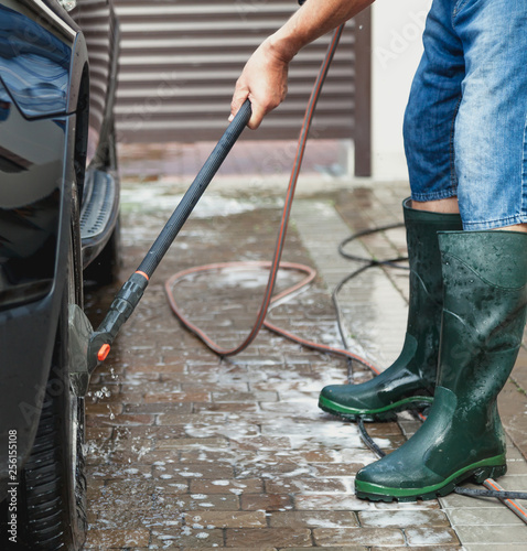 man washes modern car in yard