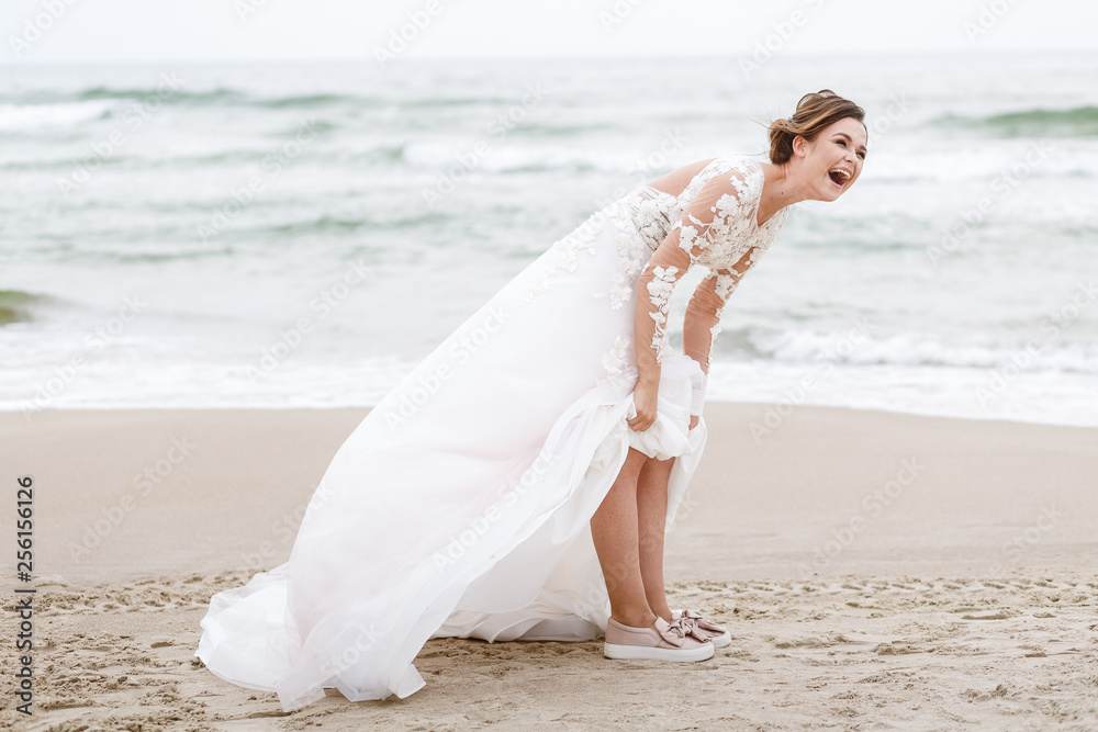positive bride runs on the sea beach on an overcast day