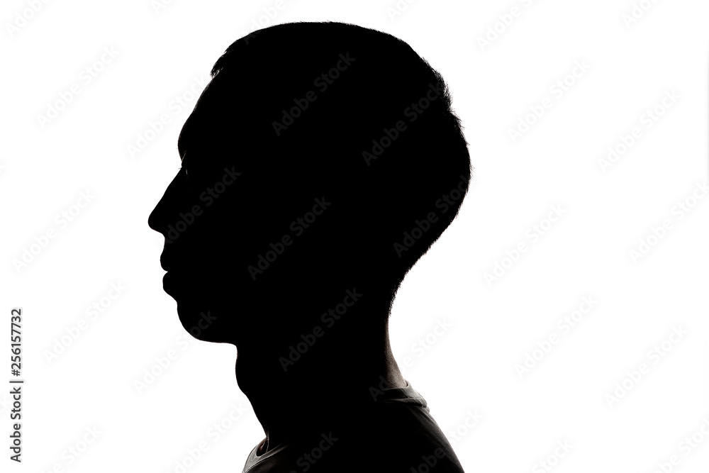 Dark silhouette profile of a young man on a white background, the concept of anonymity