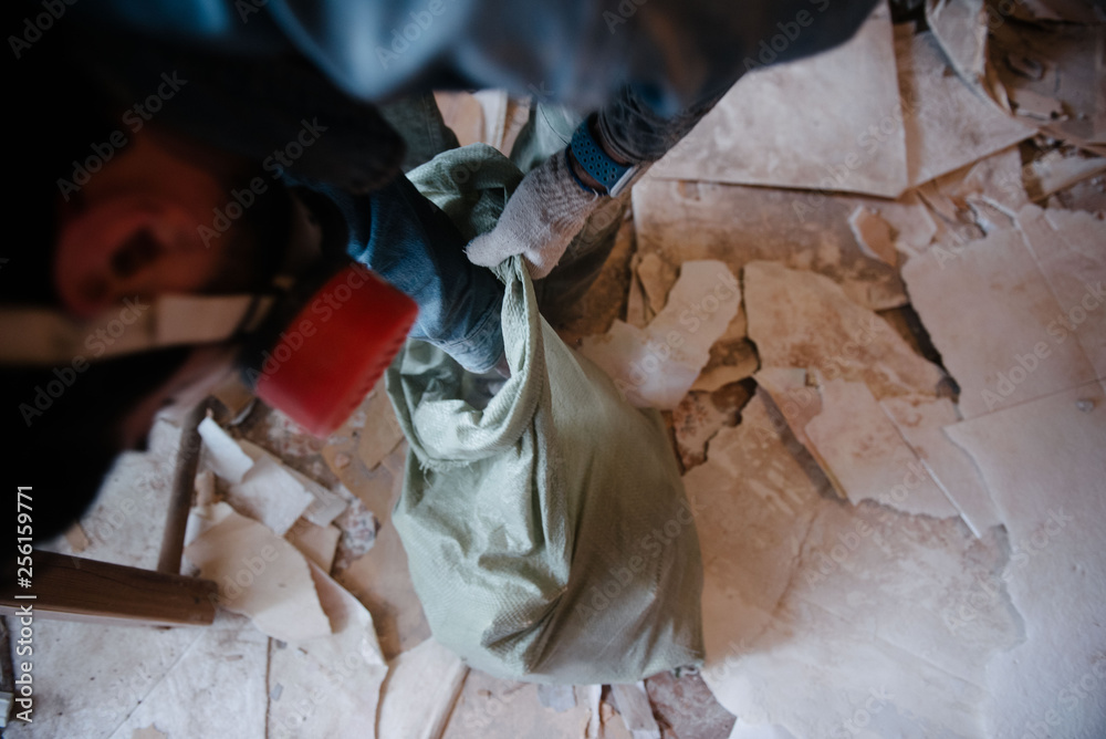 Worker cleans the trash in the apartment in the bag