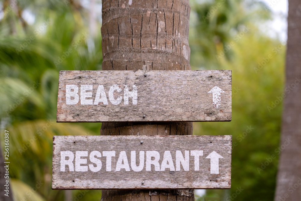 Wooden sign give direction to restaurant and beach, Thailand. Close up