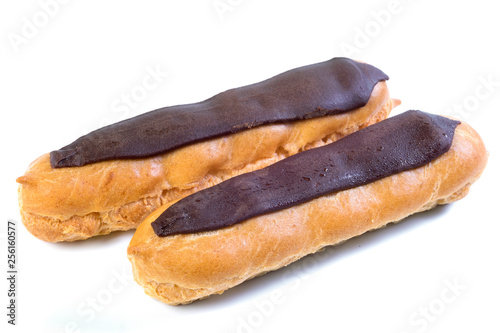 Two eclairs with dark chocolate with custard inside on a white background.
