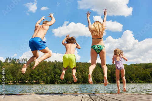 Glückliche Familie springt in einen See