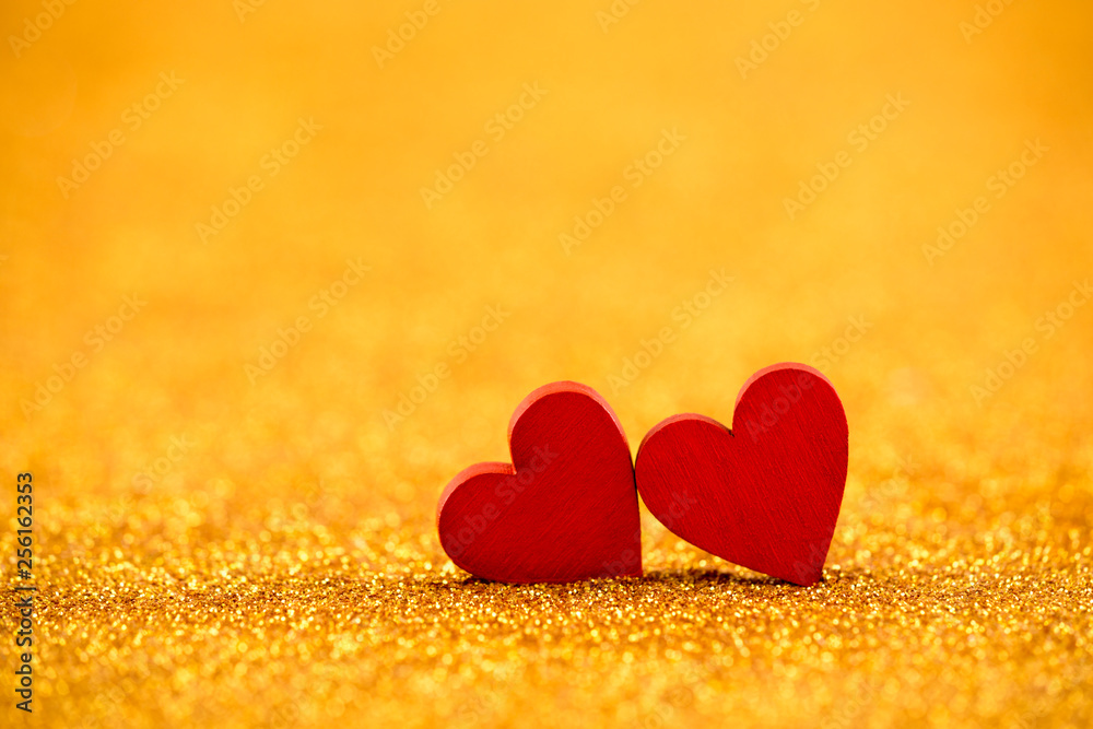 Two red hearts on golden glitter background in love concept Two red hearts on golden glitter background in love concept