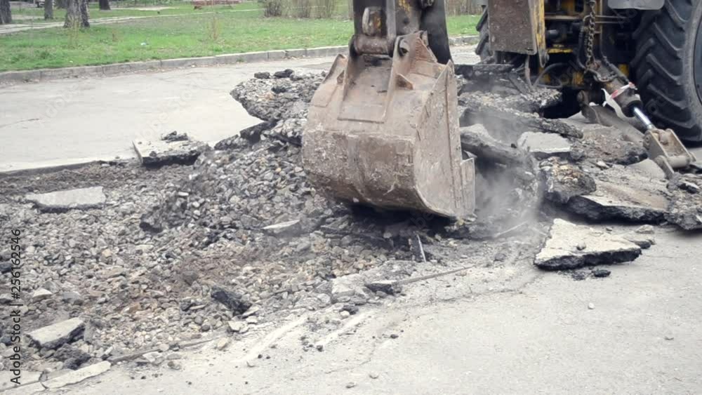 Tractor bucket breaks asphalt Tractor bucket breaks asphalt