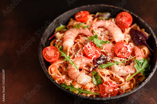 Tasty pasta with shrimp and tomato on a frying pan