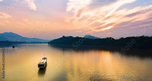 Stunning aerial view of a tourists boat sailing along the Mekong river at sunset in Luang Prabang, Laos. © Travel Wild