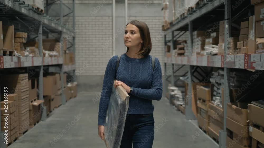 Young female carring packing with goods in shop warehouse. Young female carring packing with goods in shop warehouse.