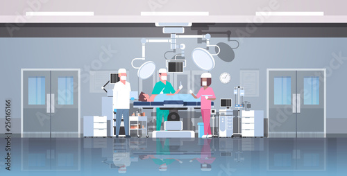 mix race surgeons team surrounding patient lying on operation table during surgery medical workers in operation room modern hospital clinic interior horizontal full length