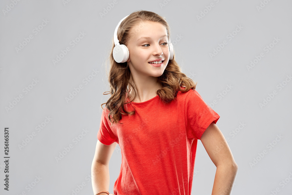 music, technology and people concept - happy teenage girl in headphones and red t-shirt over grey background