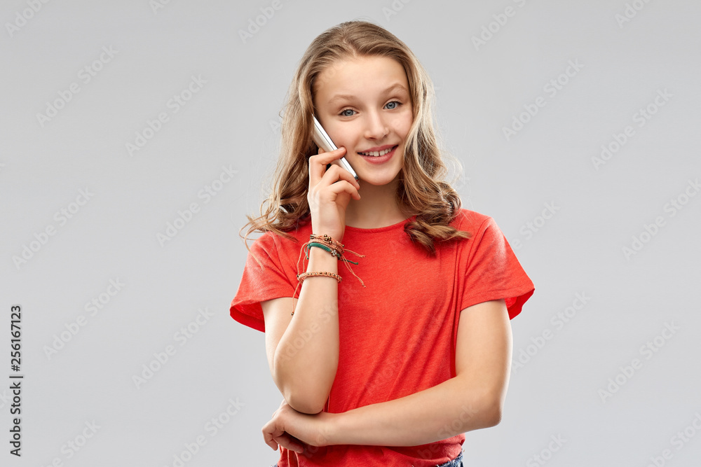 technology, communication and people concept - smiling teenage girl with long hair in red t-shirt calling on smartphone over grey background technology, communication and people concept - smiling teenage girl with long hair in red t-shirt calling on smartphone over grey background