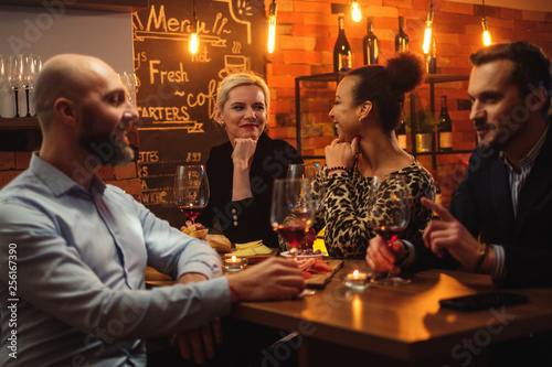 Group of friends having fun talk behind bar counter in a cafe